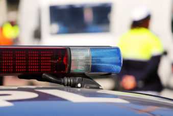 Red and blue siren police car during the roadblock with policemen in uniform