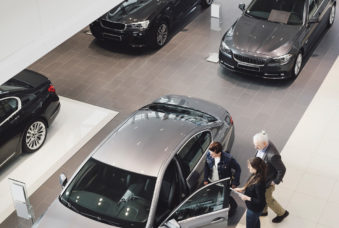 High angle view of saleswoman explaining to customers at car showroom