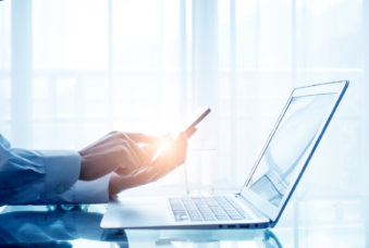 Businessman using mobile phone and laptop in office