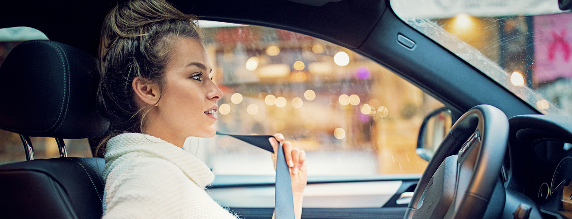 Young girl is fastening her seat belt in a rainy day - LoJack