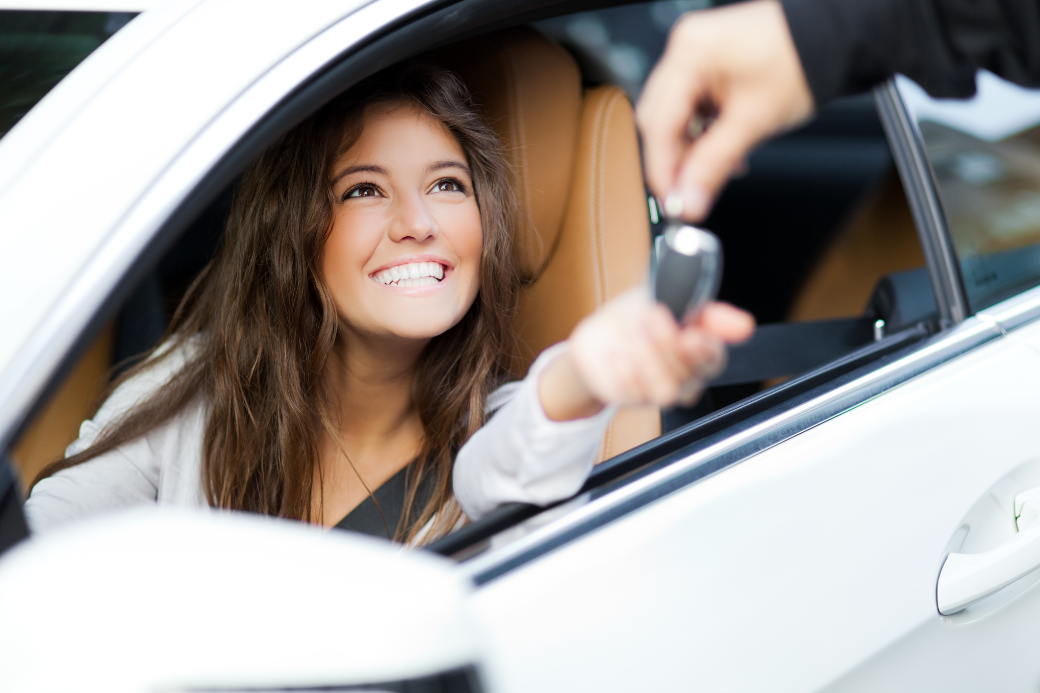 Young woman receiving the keys of her new car