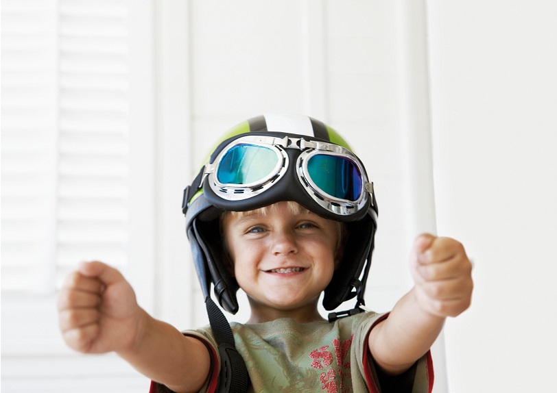 Noordhoek, South Africa --- Young boy wearing helmet pretending to drive a car --- Image by © Bruno Obmann/Corbis